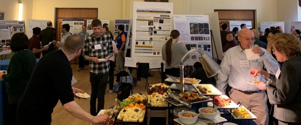 Core Day 2019, with snacks and attendees in the foreground and core facility posters in the background.